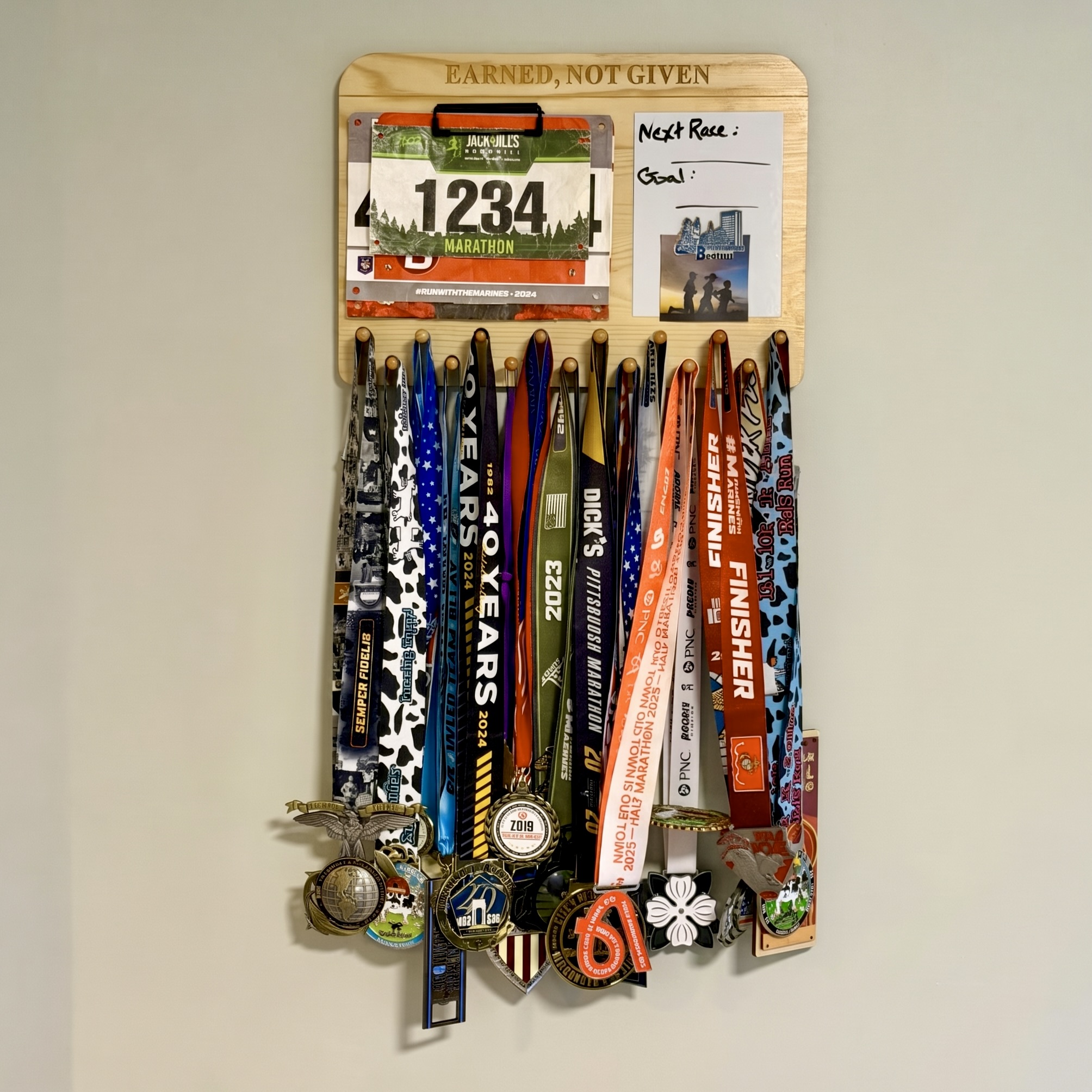 Medal display mounted on a wall and filled with layered race medals