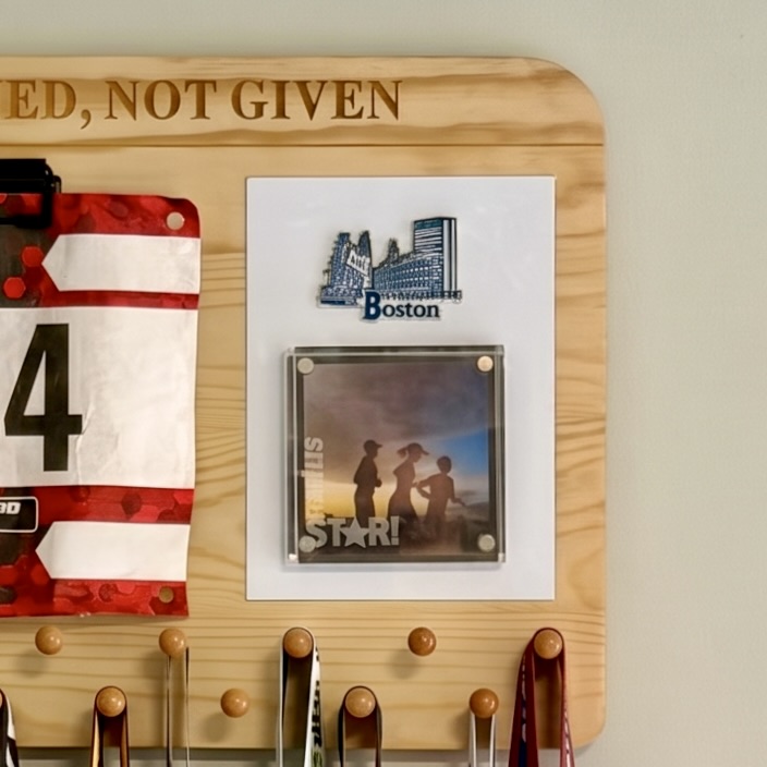 Close view of keepsake magnets holding a running photograph on the medal display whiteboard