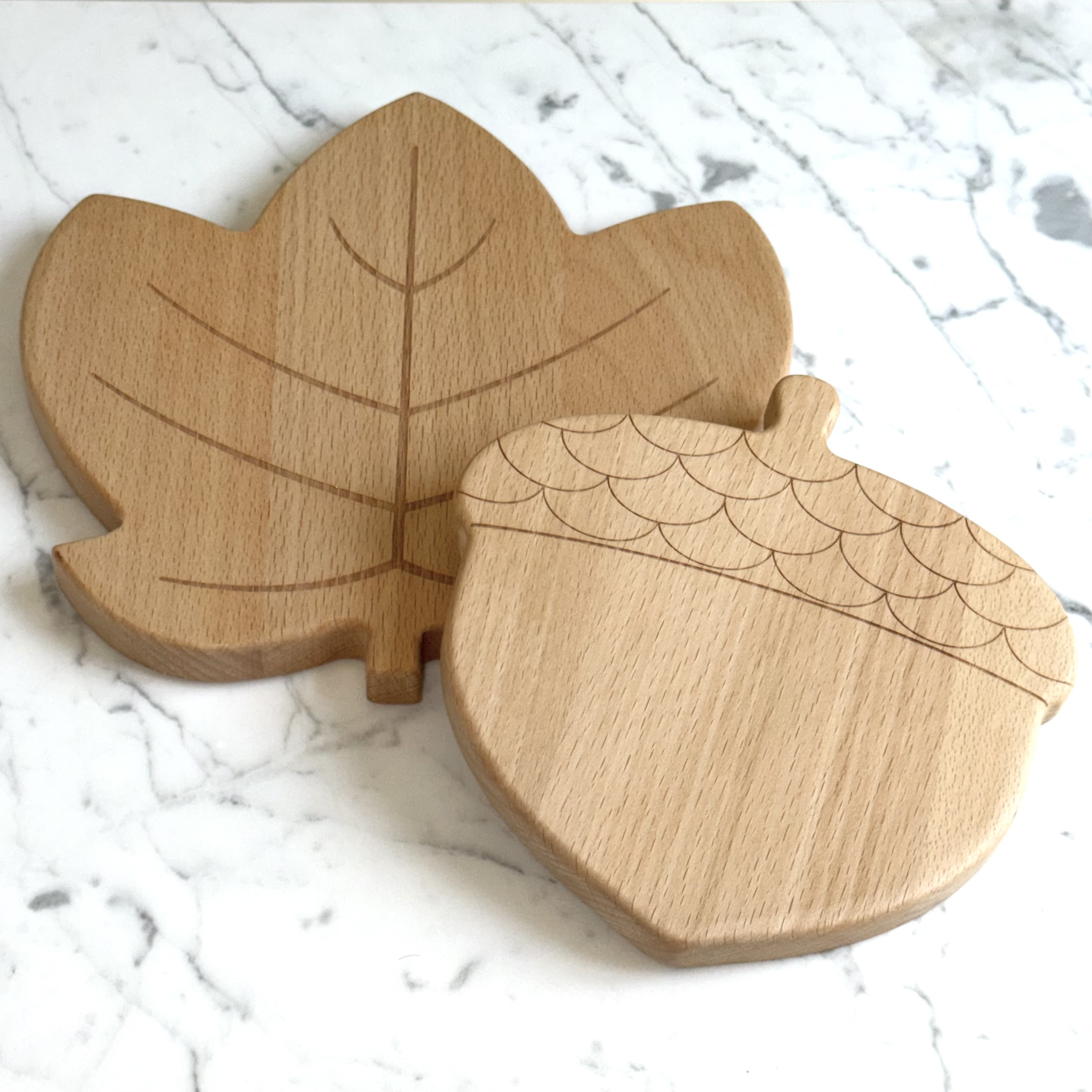 Leaf and acorn solid wood magnetic trivet set on a light marble surface