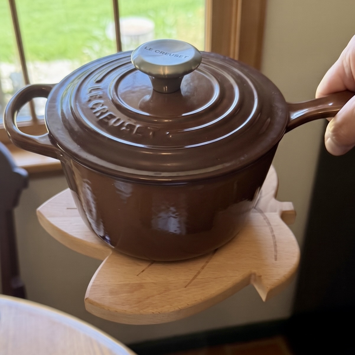 Brown saucepan lifted with the leaf trivet magnetically attached beneath it