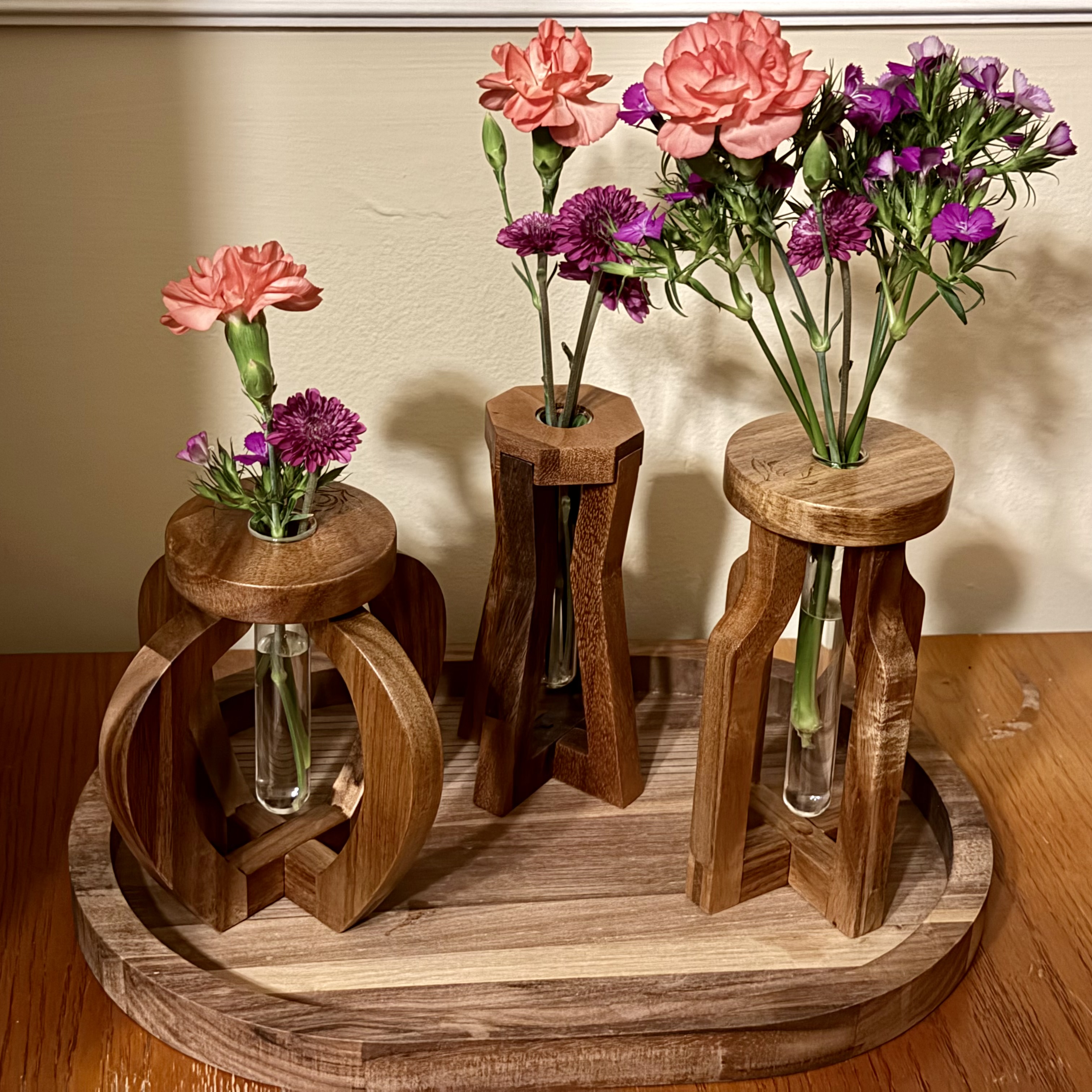Three sculptural wooden vase studies holding fresh flowers